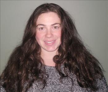 female employee with long brown hair and wearing a grey sweater