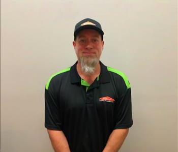 male employee in a black shirt, ball cap, and long beard in front of a white background